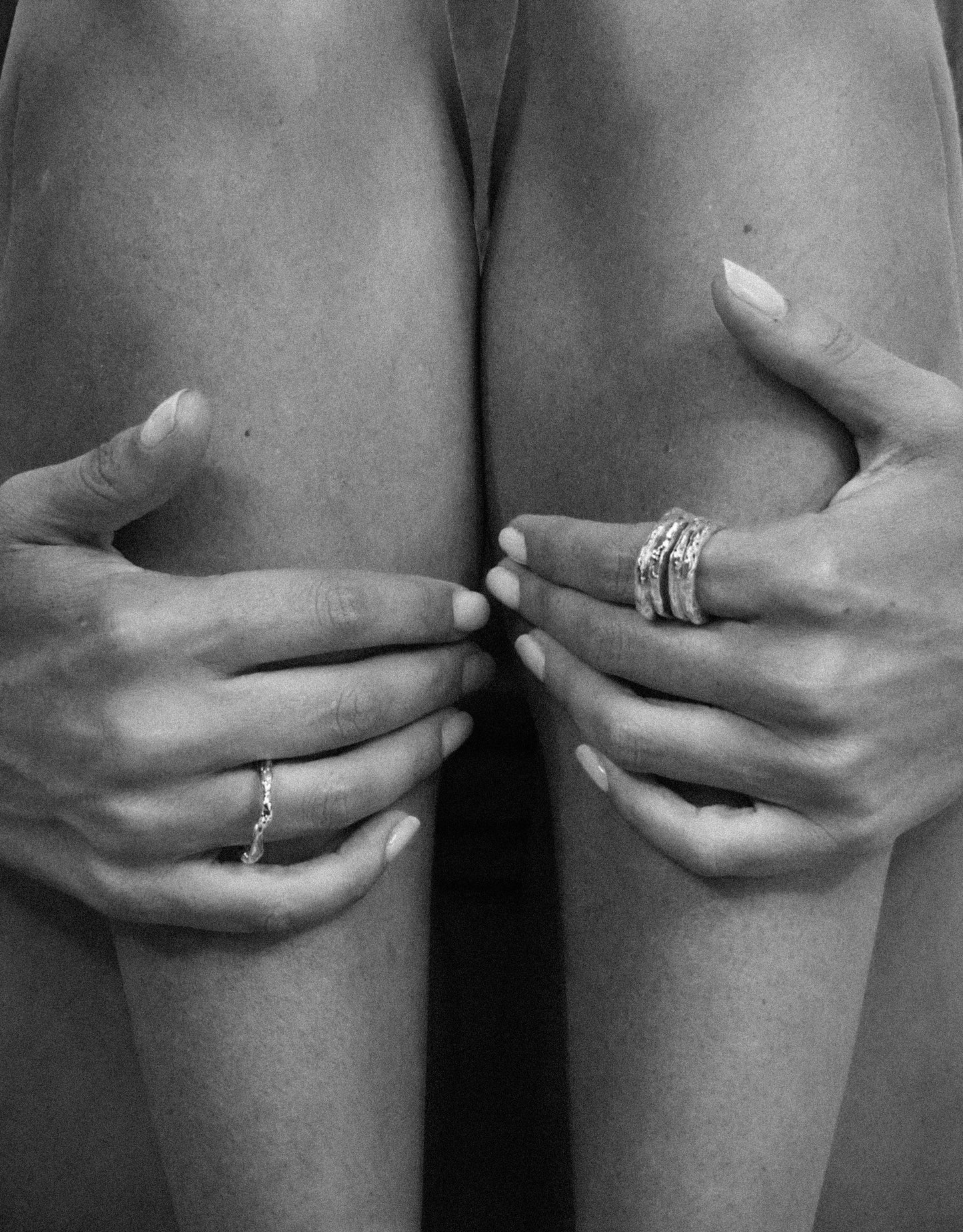 Manos sujetándose las rodillas con varias de las joyas hechas a mano de The Ink