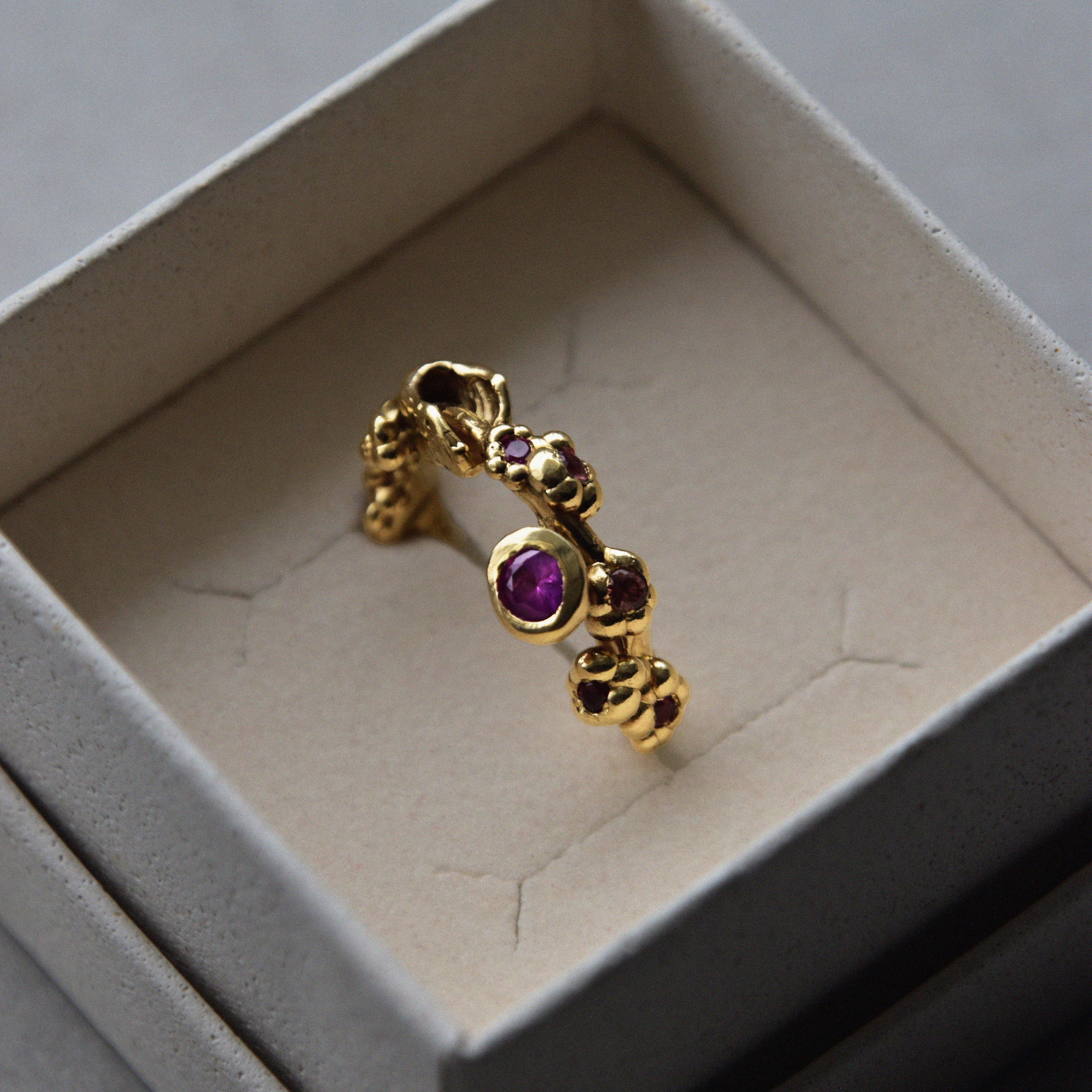 Anillo bañado en oro hecho a mano con incrustaciones de piedras preciosas en la caja de The Ink