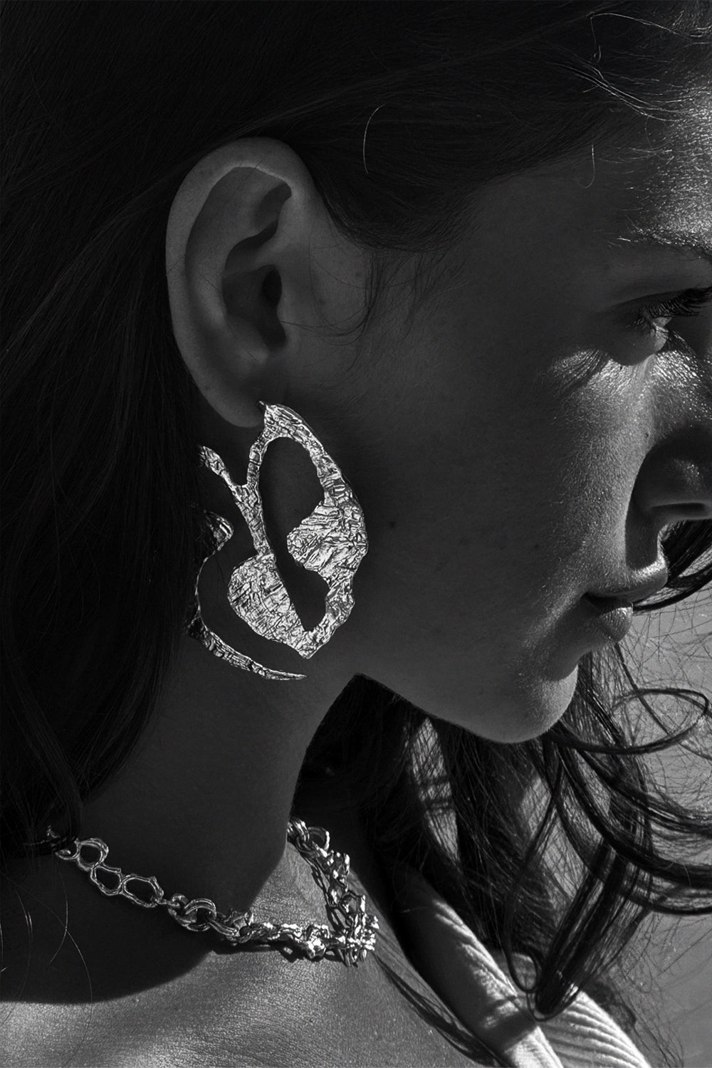 Modelo en blanco y negro con pendientes de plata hechos a mano y collar artesanal de diseño exclusivo