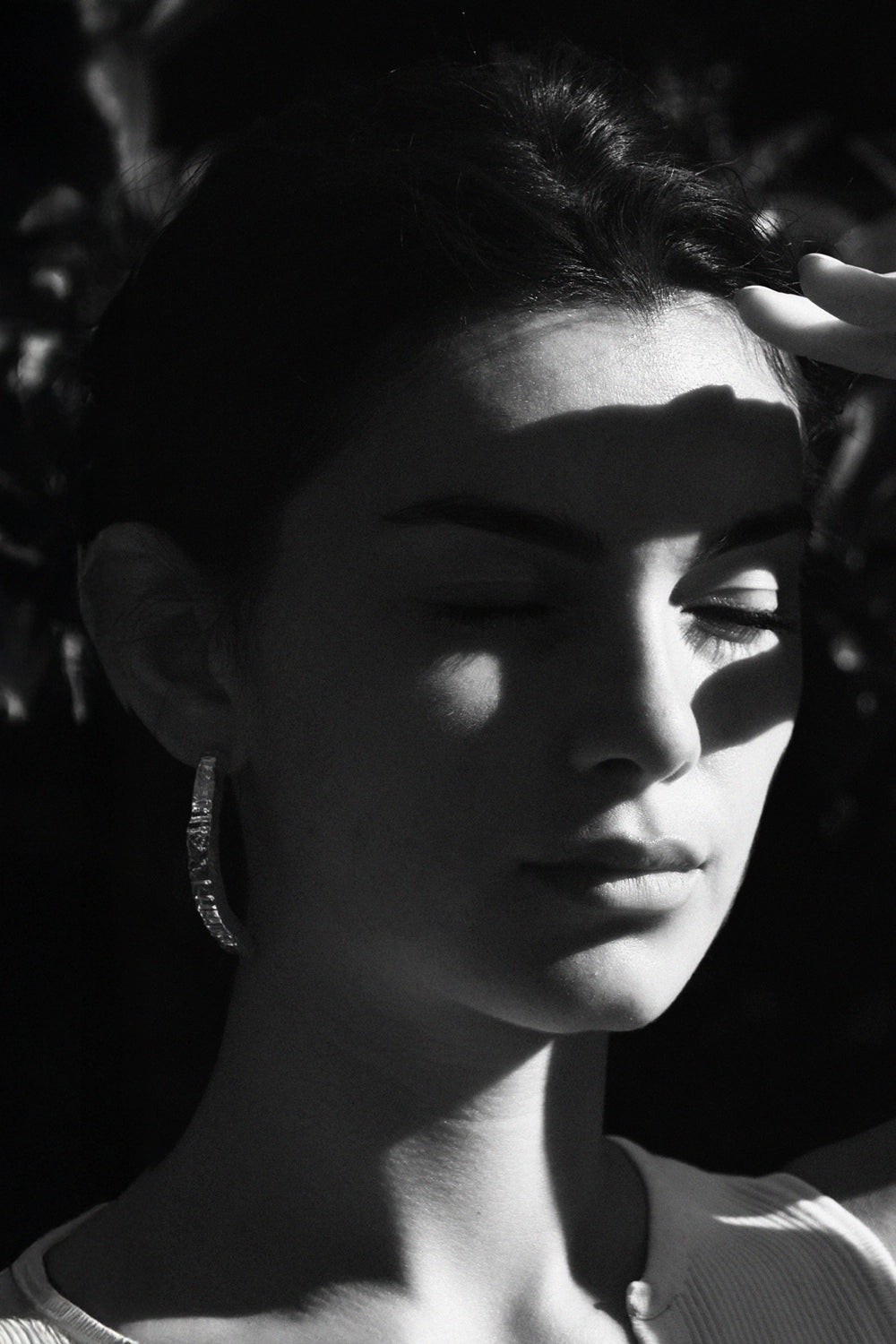 Foto en blanco y negro de una mujer tapándose el sol mostrando su pendiente exclusivo de plata