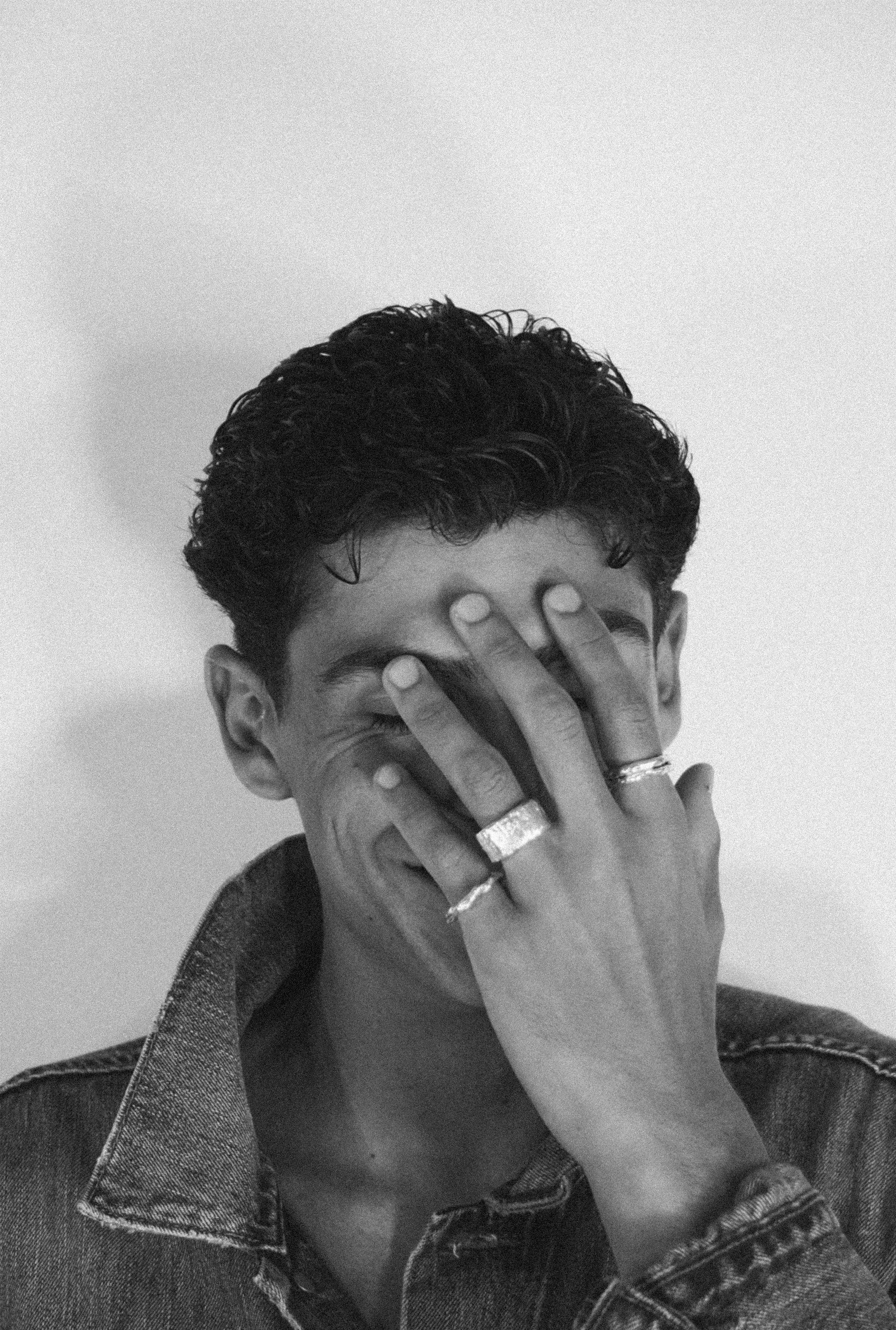 Foto de modelo riéndose y tapándose la cara con anillos de plata de The Ink